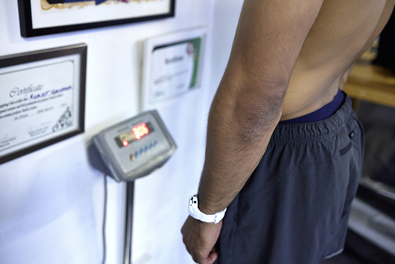 Man checking his weight as part of managing excess chest fat